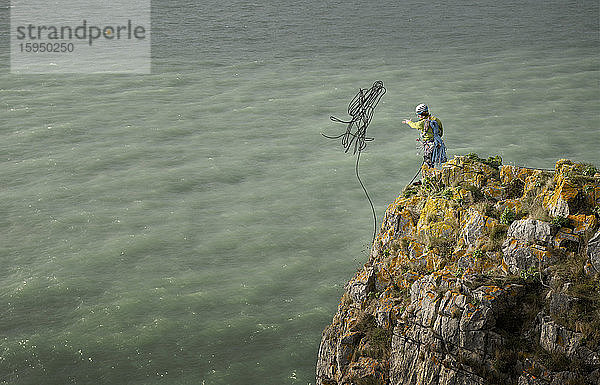 Felskletterer wirft Seil von Klippe aufs Meer