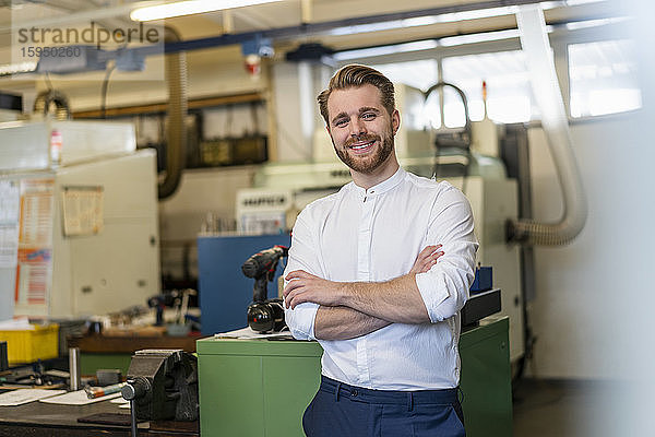 Porträt eines lächelnden jungen Mannes in einer Fabrik