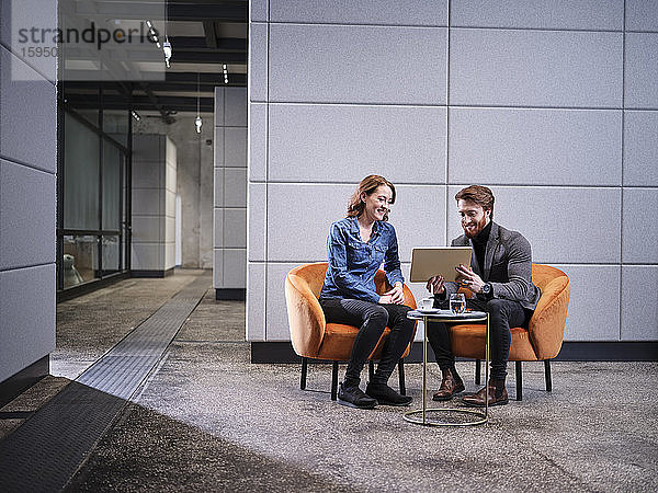 Geschäftsmann mit Tablett und Geschäftsfrau bei einer Besprechung im modernen Büro