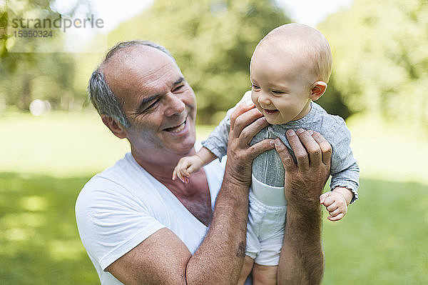 Lächelnder älterer Mann hält kleines Mädchen in einem Park