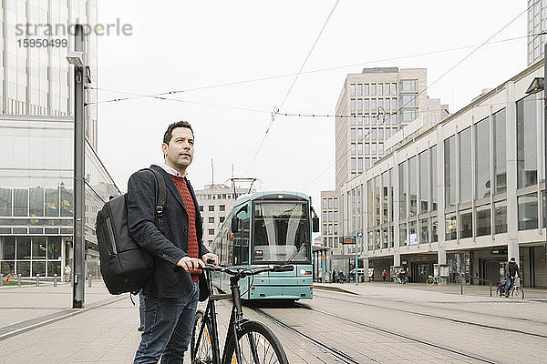 Unternehmer mit Fahrrad steht gegen Seilbahn in der Stadt  Frankfurt  Deutschland
