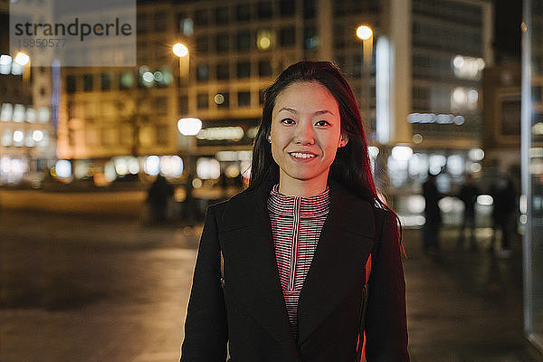 Porträt einer selbstbewussten jungen Frau in der Stadt bei Nacht  Frankfurt  Deutschland