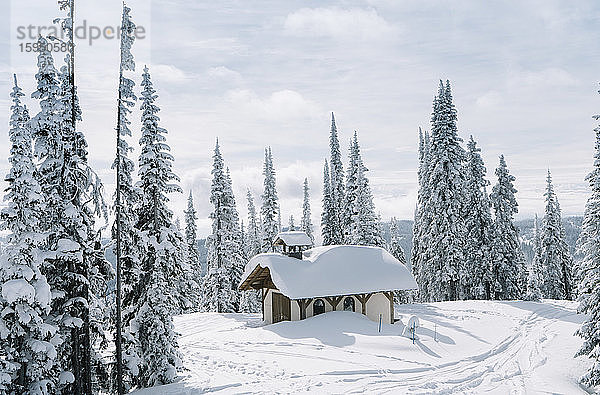 Abgeschiedenes Haus in schneebedecktem Bergwald