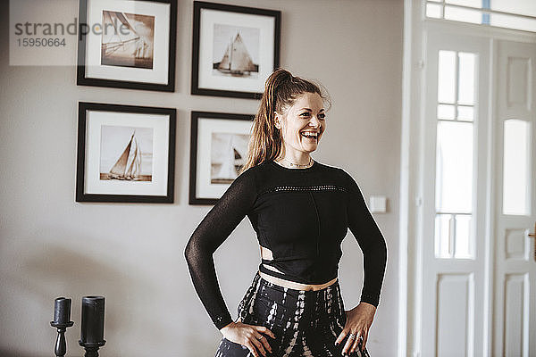 Porträt einer lachenden Frau  die zu Hause Yoga praktiziert