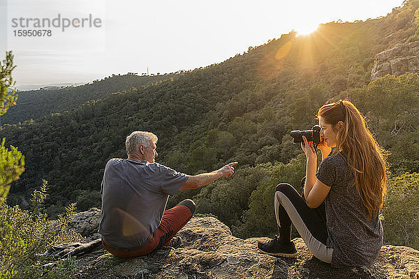 Junge Frau fotografiert ihren Vater bei Sonnenuntergang in den Bergen