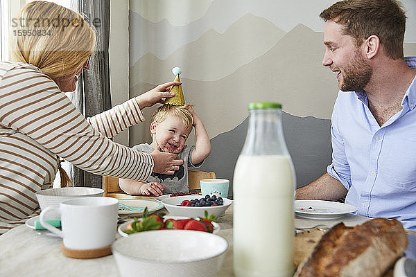Porträt eines kleinen Jungen  der sich mit seinen Eltern am Frühstückstisch vergnügt