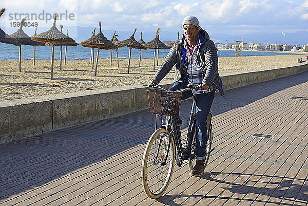 Mann fährt im Winter mit dem Fahrrad an der Strandpromenade