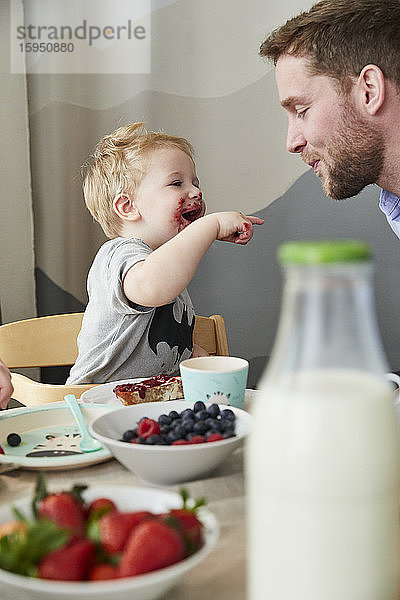 Kleiner Junge mit Vater amüsiert sich am Frühstückstisch