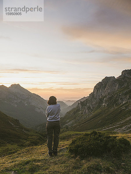 Spanien  Kantabrien  Junge Frau bewundert das Tal in den Picos de Europa im stimmungsvollen Morgengrauen