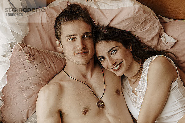 Porträt eines glücklichen jungen Paares im Bett liegend