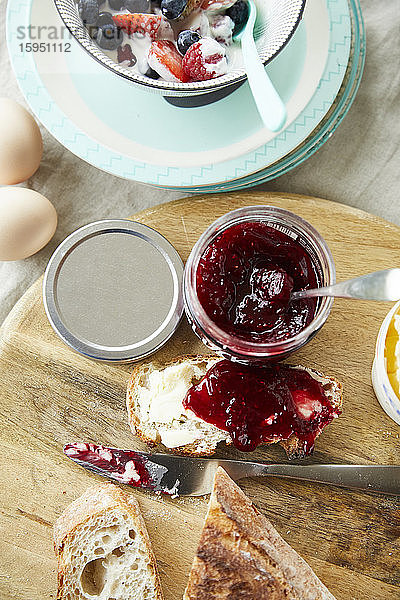 Brot mit Marmelade und Schüssel mit Obstmüsli auf dem Frühstückstisch