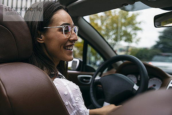 Lächelnde junge Frau fährt Cabriolet in der Stadt