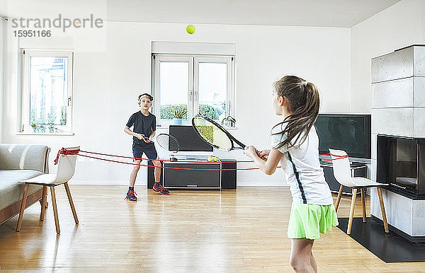 Bruder und Schwester spielen zu Hause Tennis  während sie während der Quarantäne Sport treiben