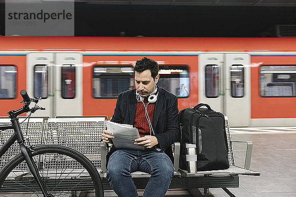 Geschäftsmann mit Fahrrad liest Dokumente  während er in der U-Bahn-Station sitzt  Frankfurt  Deutschland