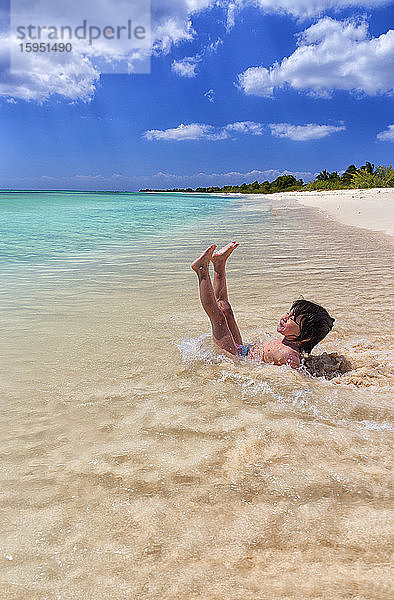 Mädchen ohne Hemd  das sich während der Sommerferien am Strand am Meer vergnügt  Punta Sur  Cozumel  Mexiko