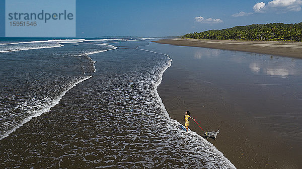 Junge Frau geht mit ihrem Hund am Strand spazieren  Costa Rica