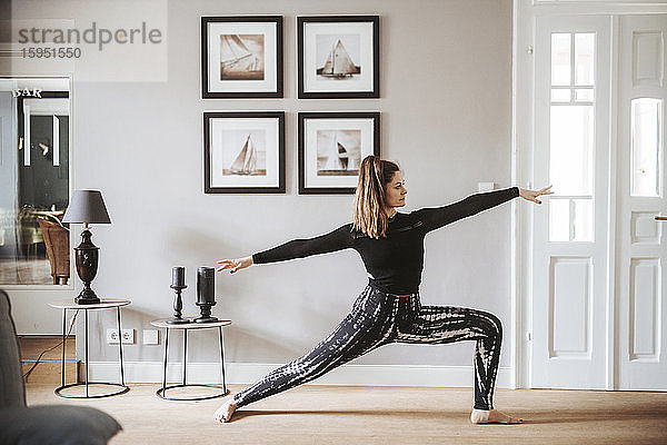 Frau  die zu Hause Yoga praktiziert  Krieger-Pose