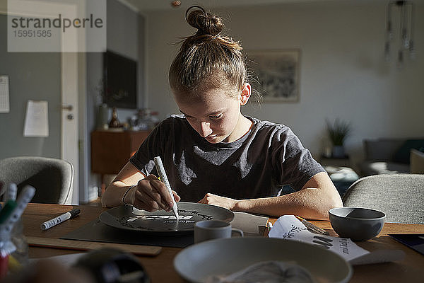 Mädchen zu Hause malt Teller mit Porzellanfarbe
