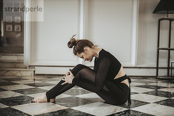 Frau praktiziert Yoga auf schwarz-weißem Boden zu Hause