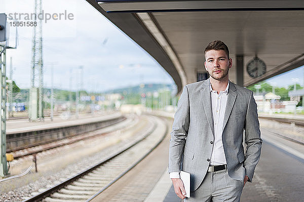 Porträt eines jungen Geschäftsmannes auf dem Bahnsteig