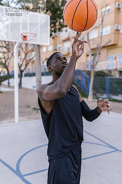 Junger Mann balanciert Basketball auf seinem Finger