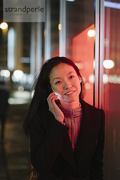Junge Frau telefoniert nachts in der Stadt