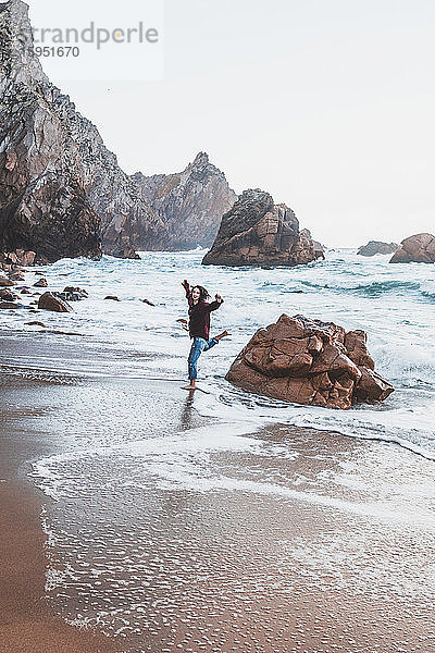Junge Frau springt vom Felsen am Praia da Ursa  Lissabon  Portugal