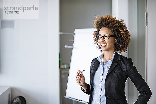 Lächelnde Geschäftsfrau leitet eine Präsentation am Flipchart im Büro