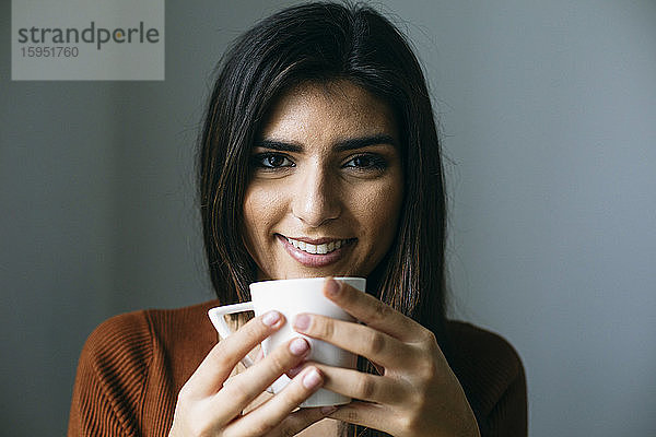 Porträt einer lächelnden Geschäftsfrau  die in der Pause im Büro Kaffee trinkt