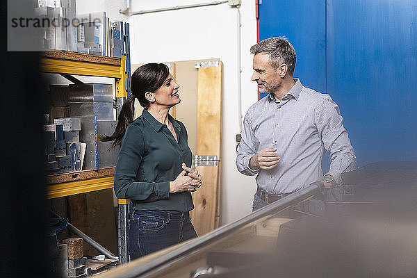 Lächelnder Geschäftsmann und Geschäftsfrau bei einer Arbeitsbesprechung im Lager einer Fabrik