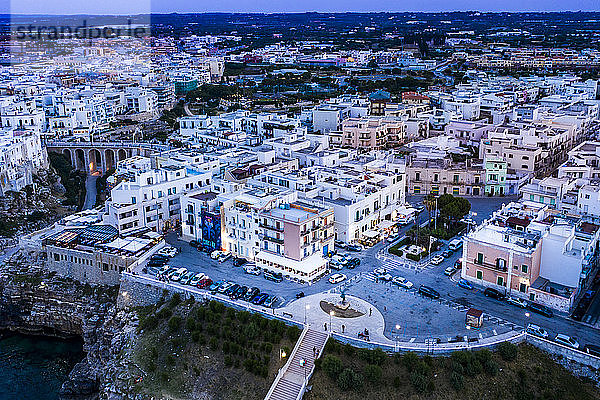 Italien  Polignano a Mare  Helikopteransicht von Gebäuden und Parkplatz der Küstenstadt in der Abenddämmerung