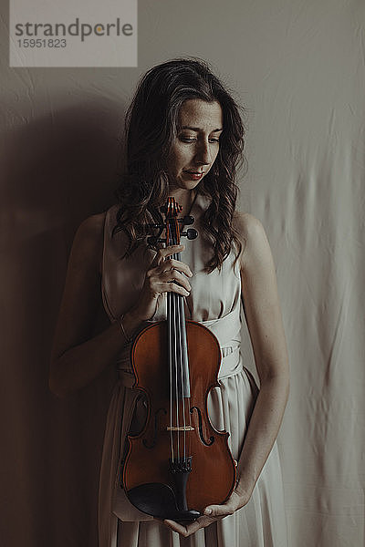 Frau hält Geige und schaut nach unten
