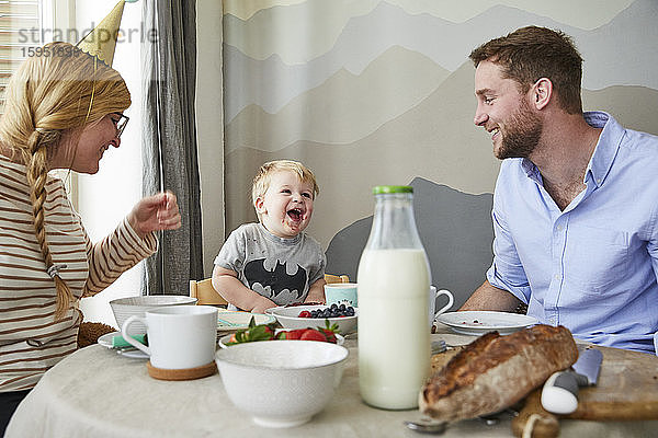 Porträt eines kleinen Jungen  der sich mit seinen Eltern am Frühstückstisch vergnügt