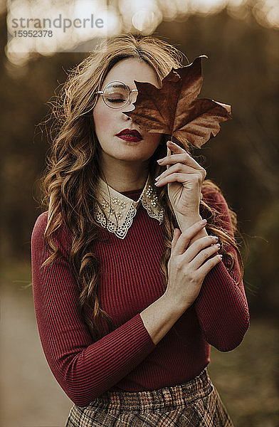 Porträt einer modischen Frau mit Herbstblatt