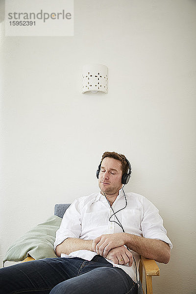 Mann  der zu Hause mit Kopfhörern Musik hört