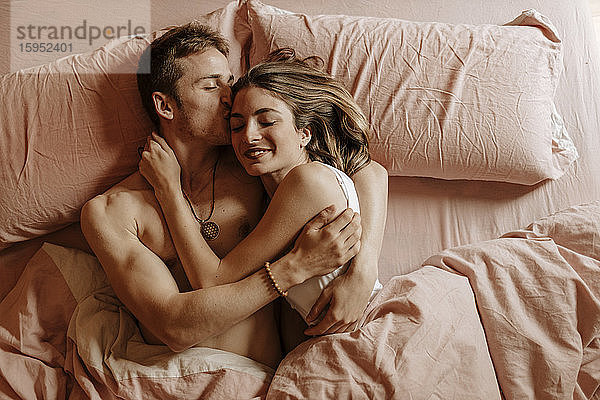 Glückliches junges Paar liegt im Bett
