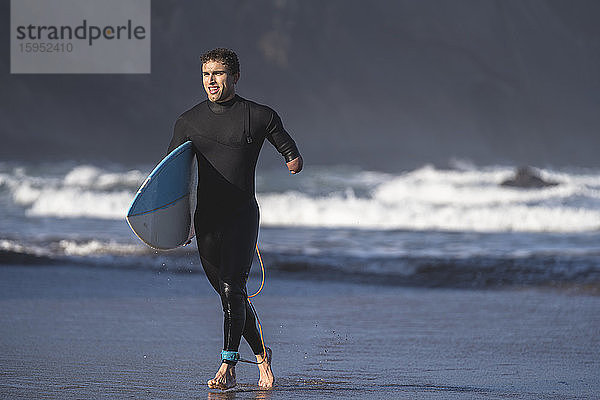 Behinderter Surfer mit Surfbrett am Strand