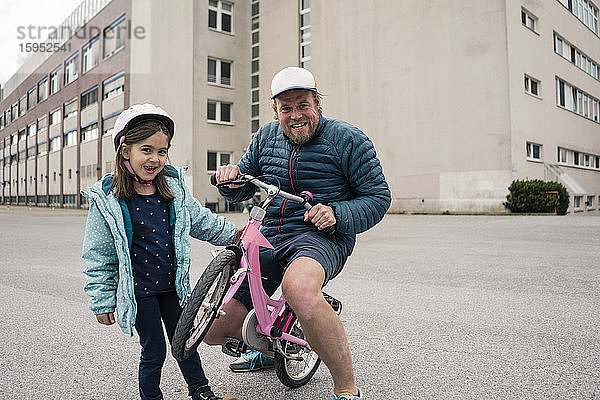 Verspielter Vater mit Tochter auf dem Fahrrad