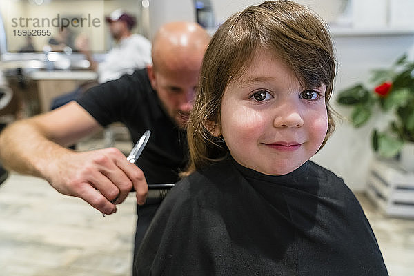 Porträt eines lächelnden kleinen Mädchens beim Haareschneiden