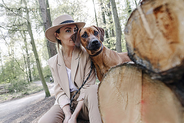 Porträt einer modischen Frau und ihres Hundes in der Natur