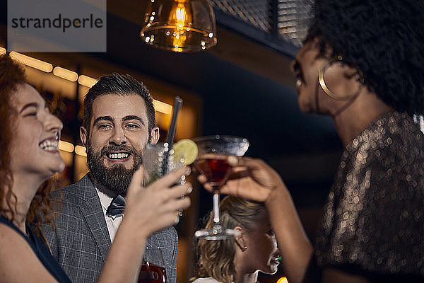 Glückliche Freunde beim geselligen Beisammensein und Cocktailtrinken in einer Bar