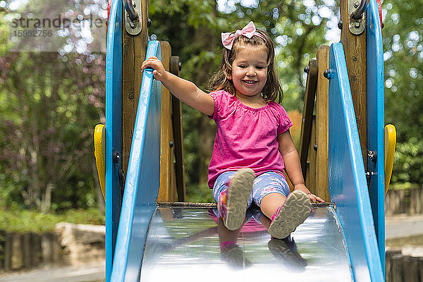 Porträt eines lächelnden kleinen Mädchens auf einer Spielplatzrutsche
