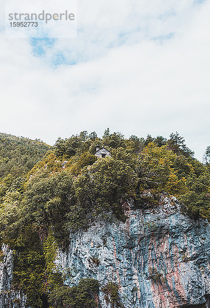 Spanien  Provinz Huesca  Wolken über einer abgelegenen Hütte am Rande eines bewaldeten Kliffs