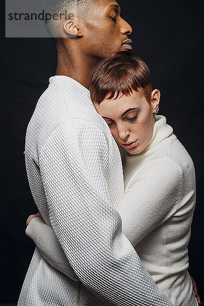 Studioporträt eines liebevollen gemischtrassigen Paares  das sich umarmt