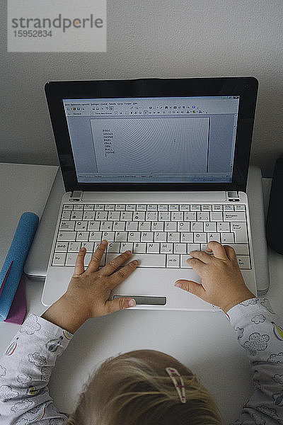 Scherenschnittansicht eines kleinen Mädchens mit Laptop zu Hause