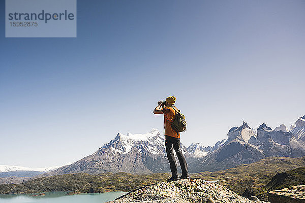 Wanderer in der Berglandschaft beim Blick durch ein Fernglas am Lago Pehoe im Torres del Paine Nationalpark  Patagonien  Chile