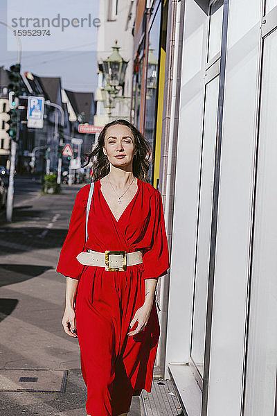 Porträt einer Frau in rotem Kleid beim Spaziergang durch die Stadt