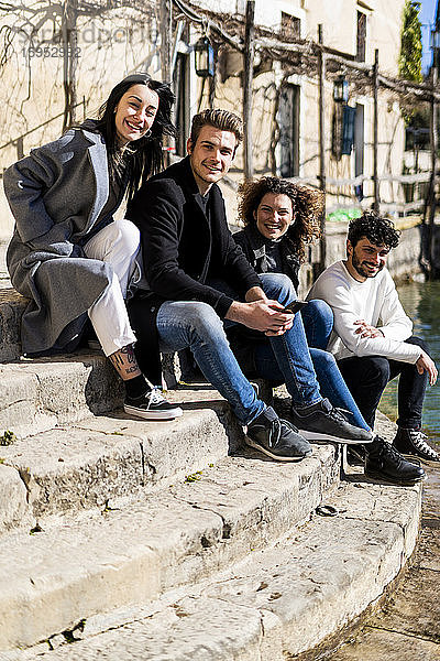 Porträt von vier Freunden  die auf einer Treppe am Gardasee sitzen  Italien