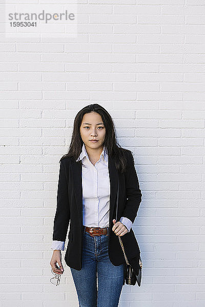 Porträt einer jungen Geschäftsfrau  die vor einer weißen Wand steht