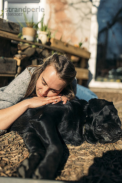 Entspannte junge Frau mit Hund im Garten